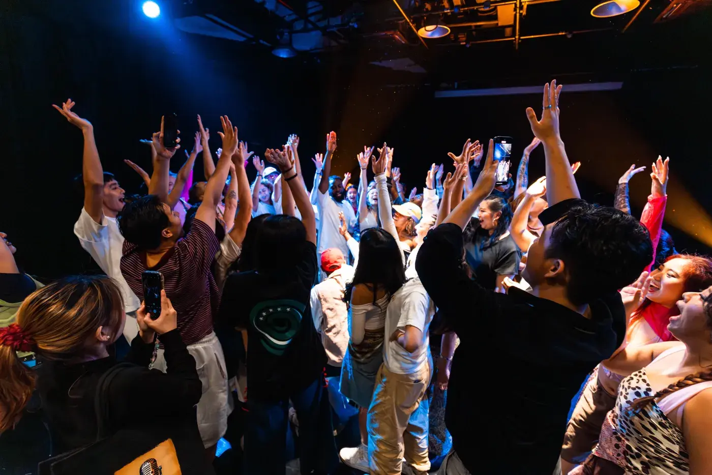 The audience at the ACE 2025 Showcase with hands raised