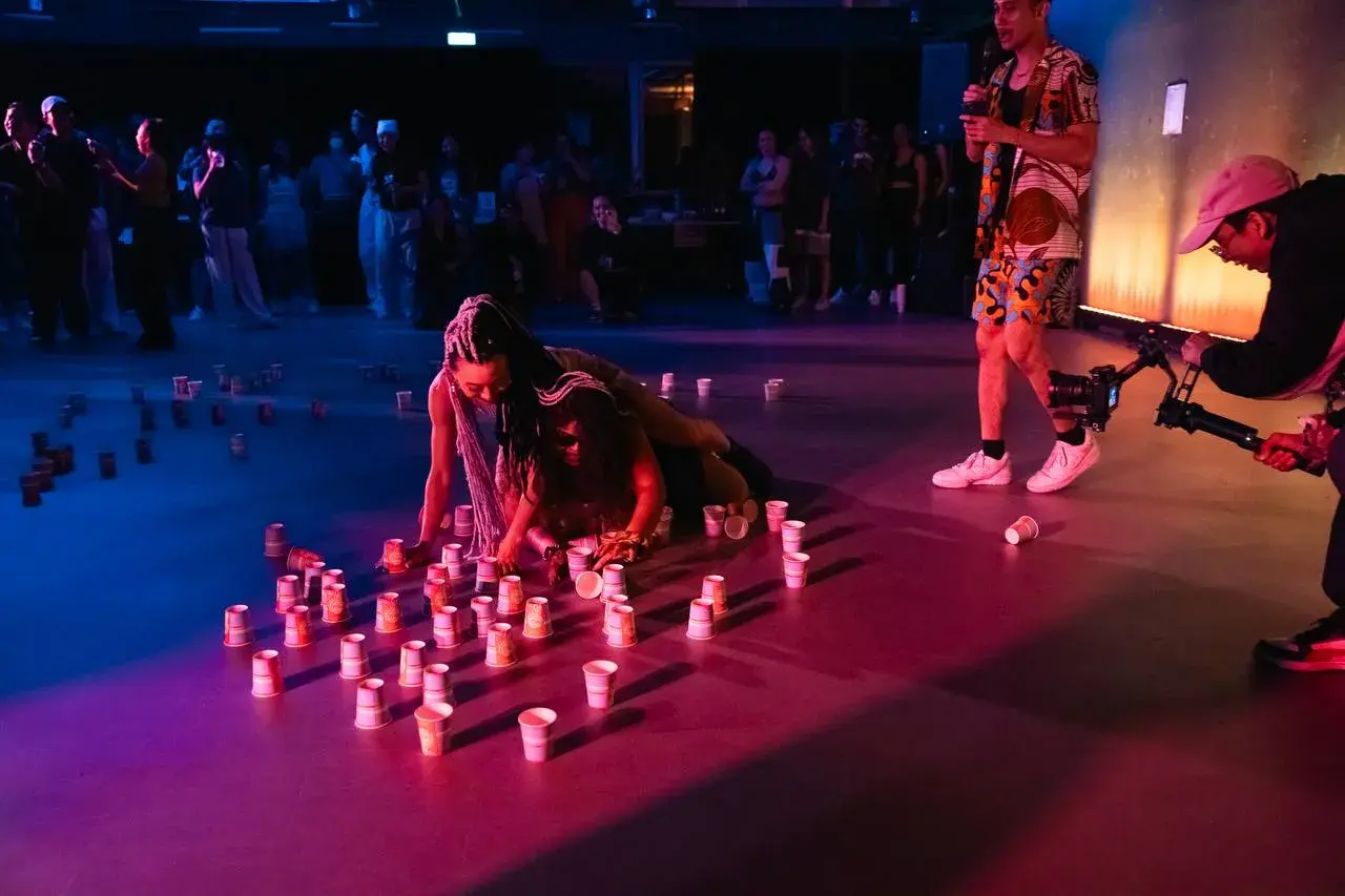 A dancer performing floorwork among lit candles at the ACE 2025 Showcase