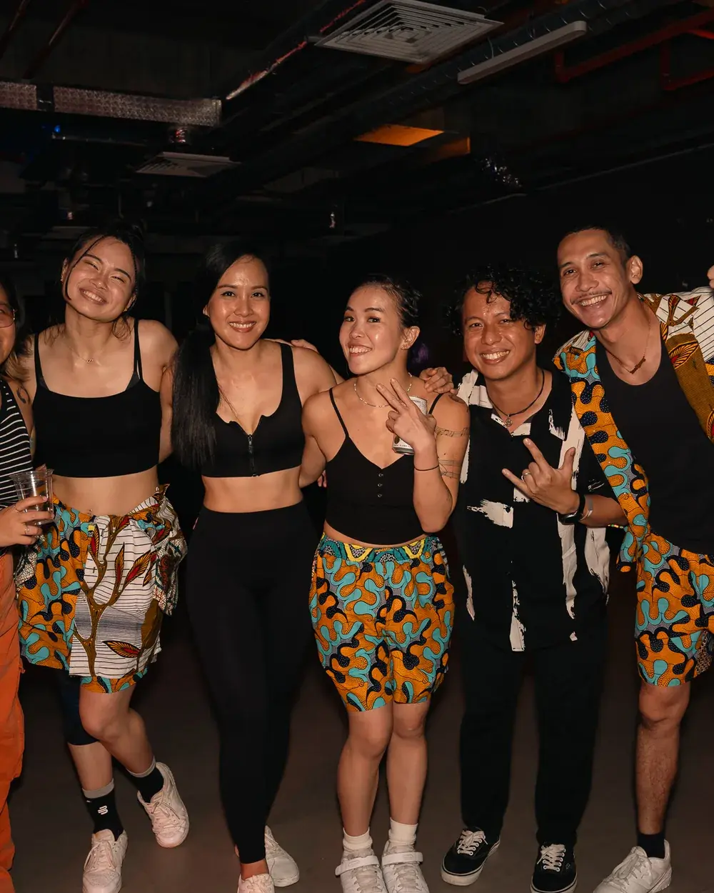 Six friends posing together in matching printed outfits at ACE 2025.