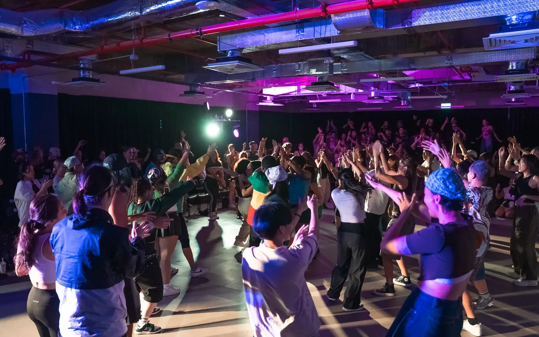 A full studio of dancers mid-routine in daylight during a workshop.